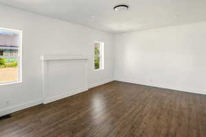 Unfurnished living room featuring dark wood-style flooring, baseboards, and visible vents