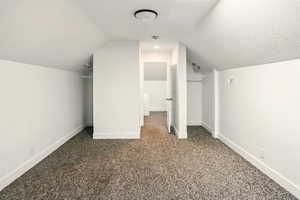 Additional living space with carpet floors, baseboards, and lofted ceiling