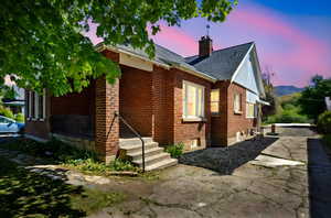 Exterior space with a shingled roof, a chimney, and brick siding