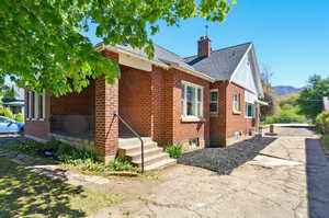 Exterior space featuring roof with shingles, a mountain view, a chimney, and brick siding