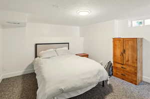 Carpeted bedroom featuring baseboards, a textured ceiling, and visible vents