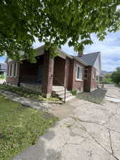 View of front of home with covered porch, a chimney, and brick siding