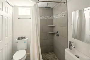 Full bathroom featuring a sink, a stall shower, toilet, and a textured ceiling