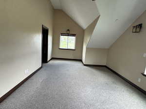 Bonus room featuring lofted ceiling, light colored carpet, and baseboards