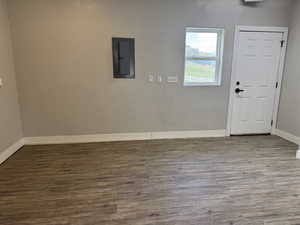 Entrance foyer with electric panel, wood finished floors, and baseboards