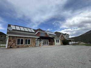 View of front of house featuring french doors, solar panels, a pergola, and stone siding