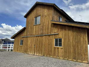 View of side of property with fence, board and batten siding, a barn, and an outdoor structure