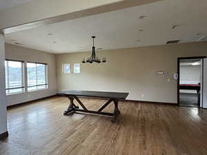 Unfurnished dining area with baseboards, wood finished floors, and a chandelier