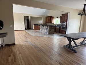 Kitchen with appliances with stainless steel finishes, a chandelier, dark countertops, light wood-style floors, and a kitchen island