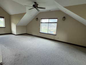 Bonus room with light carpet, lofted ceiling, healthy amount of natural light, and baseboards