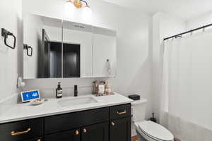 Bathroom featuring vanity, toilet, curtained shower, and visible vents