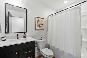 Full bathroom with shower / bath combo with shower curtain, toilet, and vanity