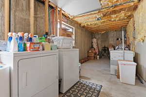 Basement featuring washer and clothes dryer, water heater, and storage area