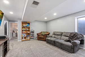 Carpeted living area with baseboards, recessed lighting, and visible vents