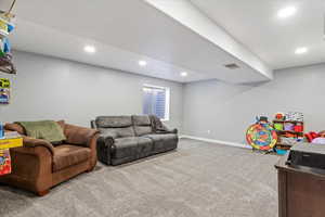 Carpeted living area featuring recessed lighting, baseboards, and visible vents