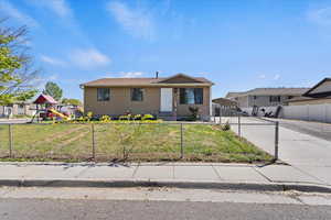 View of front of property featuring a detached carport, a fenced front yard, concrete driveway, and a front lawn