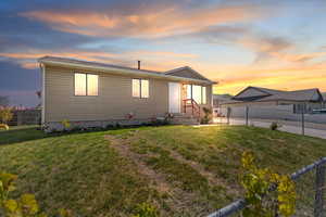 View of front of home with a lawn and fence