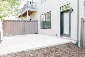 View of patio with fence and a balcony