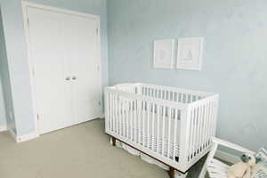 Bedroom with a crib, carpet, and a closet