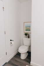 Bathroom with baseboards, wood finished floors, and toilet
