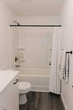 Bathroom featuring vanity, shower / bath combo, toilet, and wood finished floors