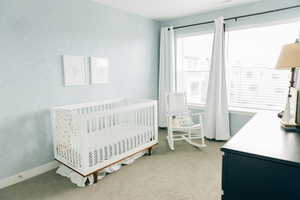 Carpeted bedroom featuring a nursery area