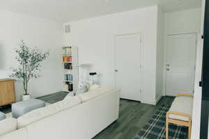 Living room featuring dark wood-type flooring, baseboards, and visible vents