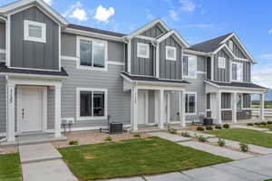 Multi unit property with a front lawn, covered porch, roof with shingles, board and batten siding, and central air condition unit