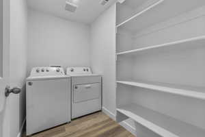 Laundry area with independent washer and dryer, laundry area, visible vents, and wood finished floors