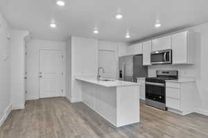 Kitchen featuring visible vents, a sink, appliances with stainless steel finishes, and light wood-type flooring