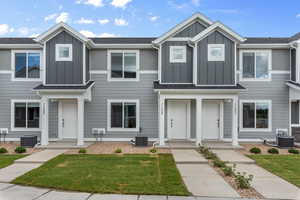 Multi unit property featuring board and batten siding, central air condition unit, and a front yard