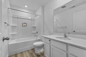 Bathroom featuring toilet, visible vents, wood finished floors, and vanity