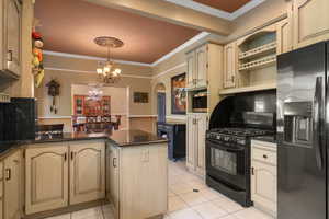 Kitchen with a peninsula, appliances with stainless steel finishes, arched walkways, and ornamental molding