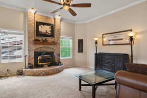 Carpeted living area featuring crown molding, a wood stove, baseboards, and ceiling fan