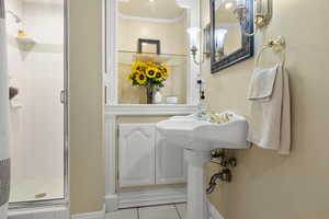 Bathroom with crown molding, baseboards, tile patterned flooring, and a stall shower