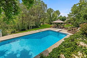 Pool with a lawn, a diving board, a gazebo, and a patio