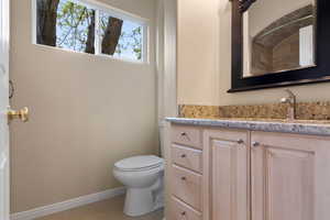 Bathroom featuring toilet, baseboards, tile patterned floors, and vanity