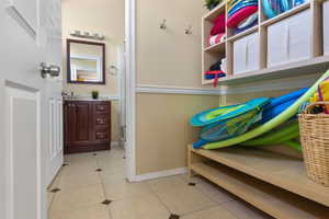 Mudroom featuring light tile patterned floors, baseboards, wainscoting, and a sink