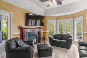 Living area featuring a high end fireplace, tile patterned flooring, french doors, and ceiling fan