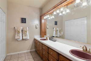 Bathroom with double vanity, a sink, baseboards, and tile patterned floors
