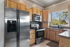 Kitchen with decorative backsplash, crown molding, appliances with stainless steel finishes, dark countertops, and a sink