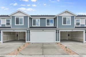 Multi unit property with driveway, a shingled roof, and a garage