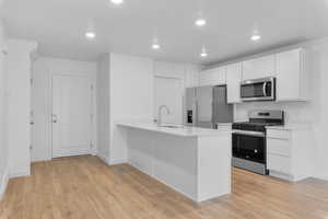 Kitchen featuring baseboards, a sink, light wood finished floors, and stainless steel appliances