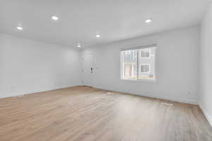 Empty room with recessed lighting, baseboards, light wood-type flooring, and visible vents