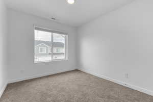 Carpeted empty room featuring visible vents and baseboards