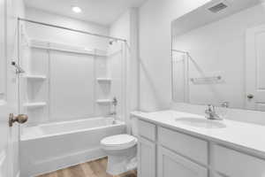 Full bath with vanity, toilet, wood finished floors,  shower combination, and visible vents