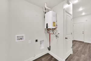 Washroom with dark wood-style floors, washer hookup, tankless water heater, electric dryer hookup, and gas dryer hookup