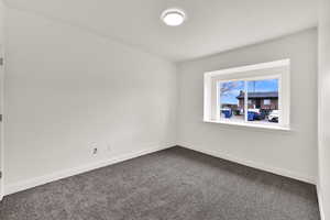 Spare room with baseboards and dark colored carpet