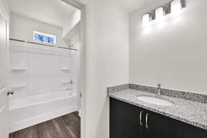 Full bathroom featuring vanity, bathtub / shower combination, and dark wood-style flooring