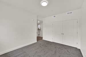 Unfurnished bedroom featuring a closet, carpet, and water heater